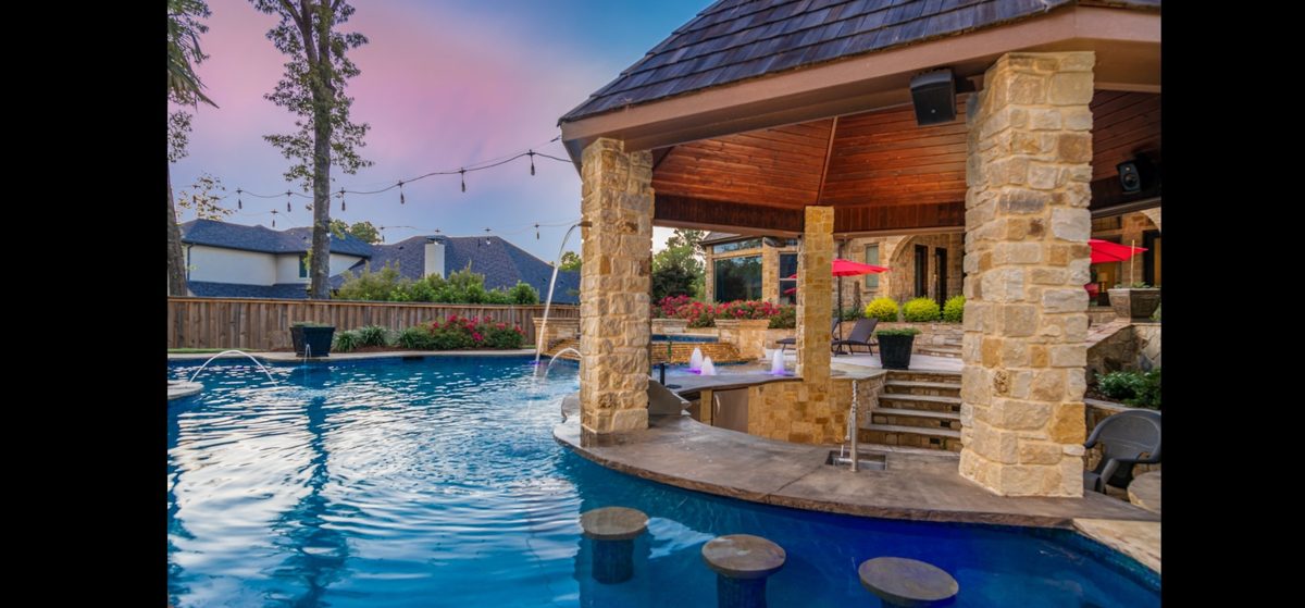 Quartz plaster pool with swim-up bar and stone columns